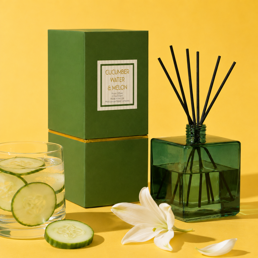 A reed diffuser set with a dark green glass bottle, black reeds, and a matching green box labeled &