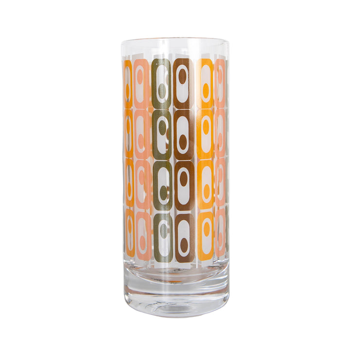 A tall highball collins cocktail glass with a vintage tiki design featuring oval shapes in pastel colors on a clear glass surface.