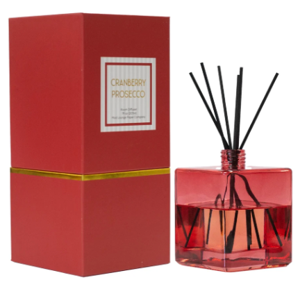 Cranberry Prosecco reed diffuser set featuring a red glass bottle with black reeds and its matching red box with a gold band.